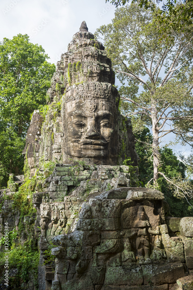 Imposing stone face smiles from the top of the East Gate at Angkor Thom, part of the Angkor Wat temple complex in Siem Reap, Cambodia