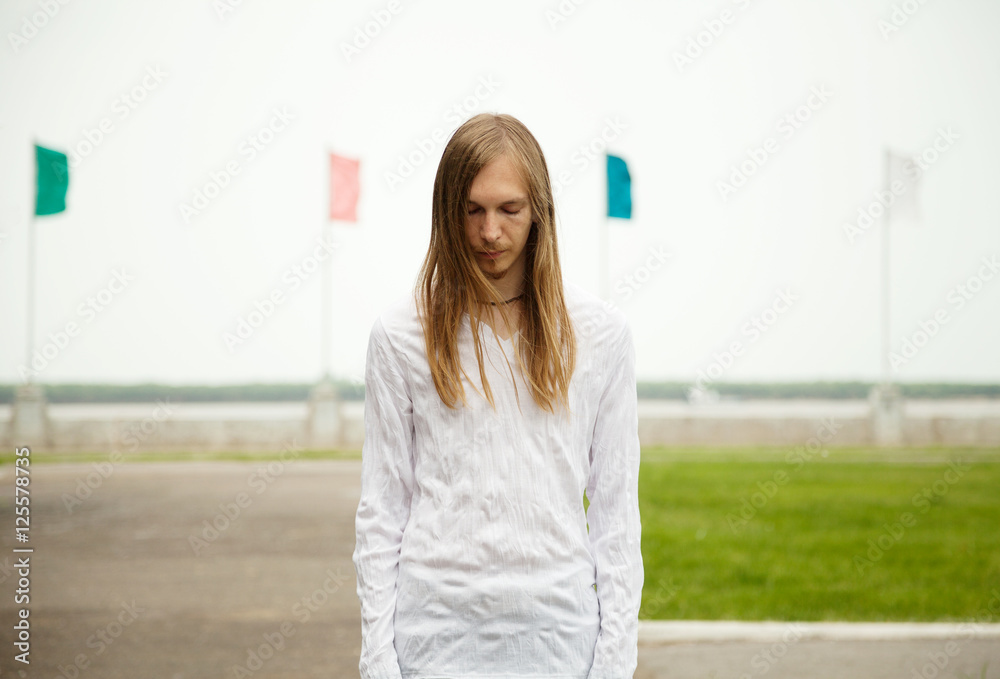 Fototapeta premium Young white man standing at the park with sad face and closed eyes. Peaceful scene
