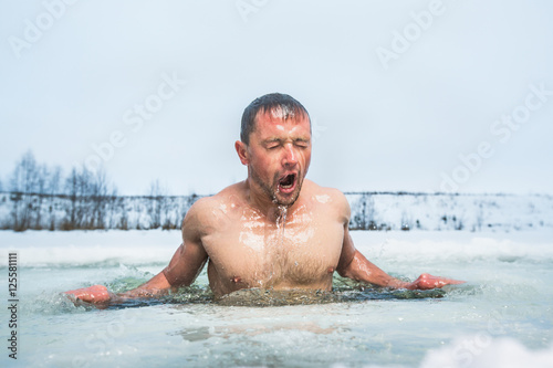 Young man swimming in the winter lake in the ice hole © Dudarev Mikhail