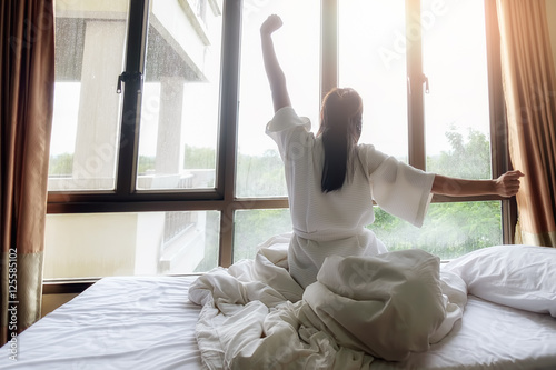 Woman stretching in bed after wake up. Soft light and soft focus to feeling relax and comfortable.