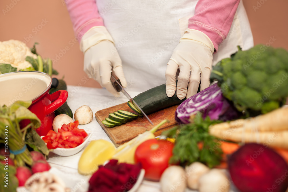 Woman with gloves slicing cucumber