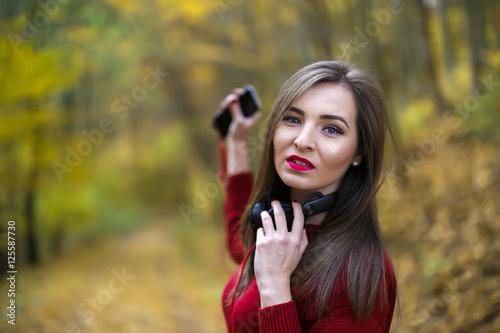 Young caucasian brunette woman with headphones outdoors on autum