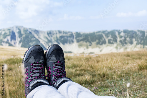 Legs with hiking boots of hiker woman traveler sitting in the summer mountain . Freedom concept