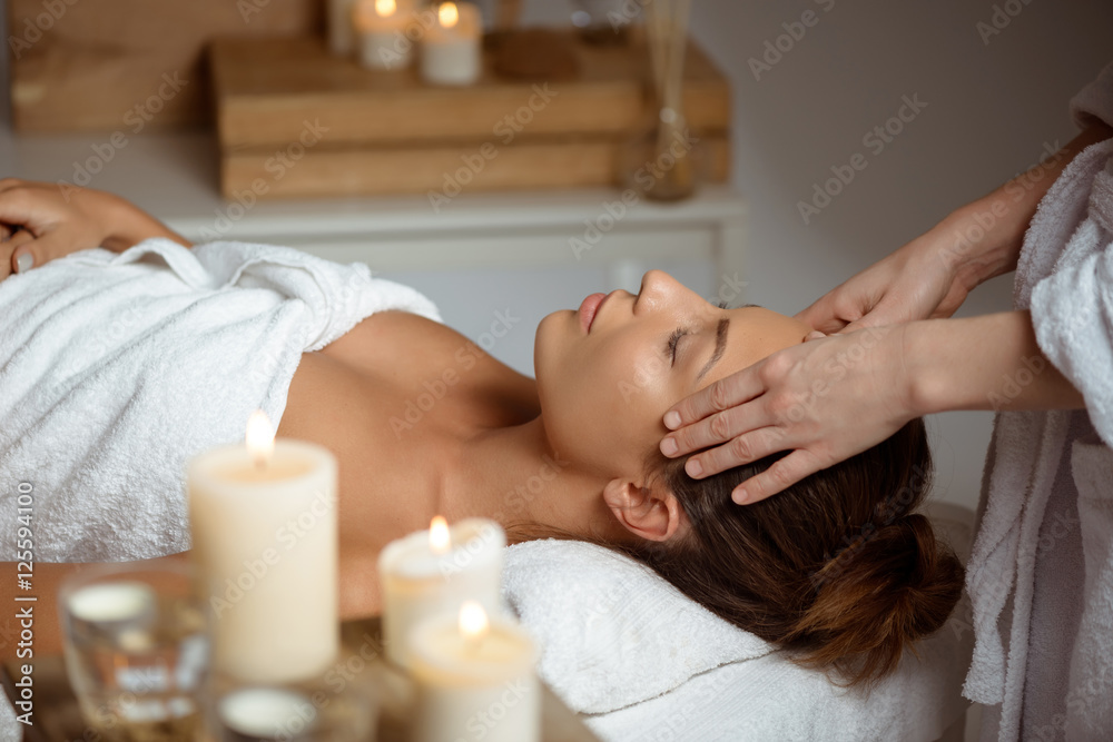 Young beautiful girl having face massage relaxing in spa salon.