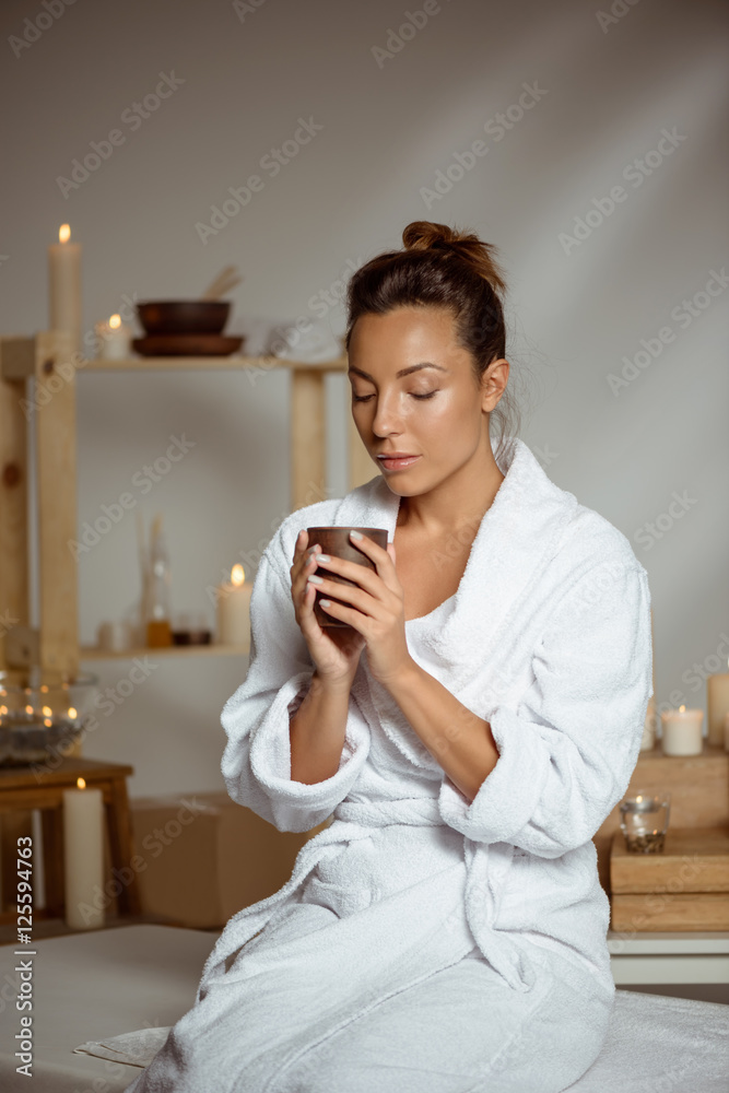Young beautiful girl holding tea cup relaxing in spa salon. Young beautiful girl holding tea cup relaxing in spa salon.