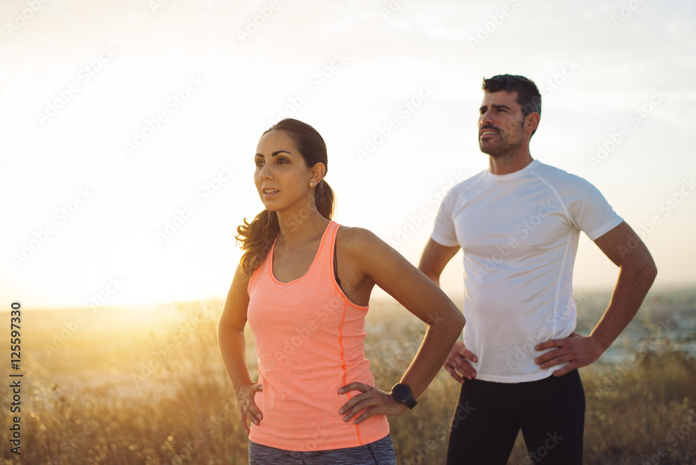 Couple of motivated athletes during outdoor workout. Runners taking a training rest. Couple of motivated athletes during outdoor workout. Runners taking a training rest.