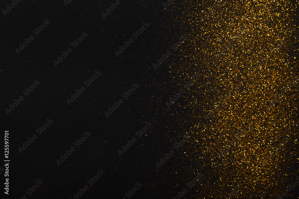 Golden glitter sand texture border on black, abstract background.