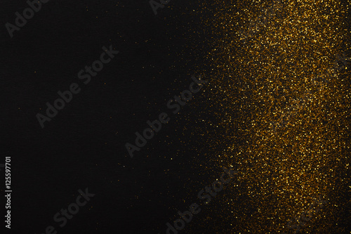 Golden glitter sand texture border on black, abstract background.