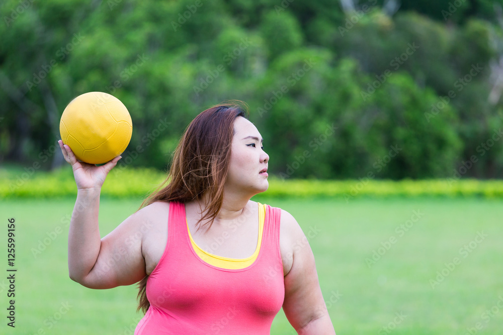 Beautiful fat woman playing dodgeball in the park.