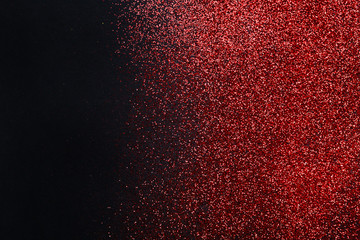 Red glitter sand texture on black, abstract background.