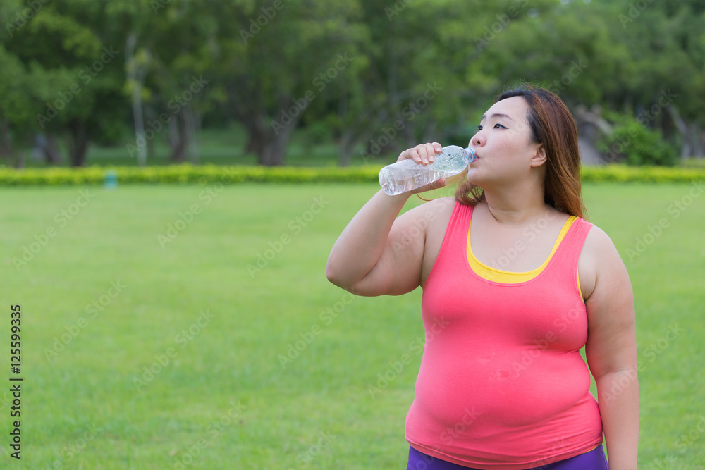 Beautiful fat woman drinking water after finish her workout. Beautiful fat woman drinking water after finish her workout.