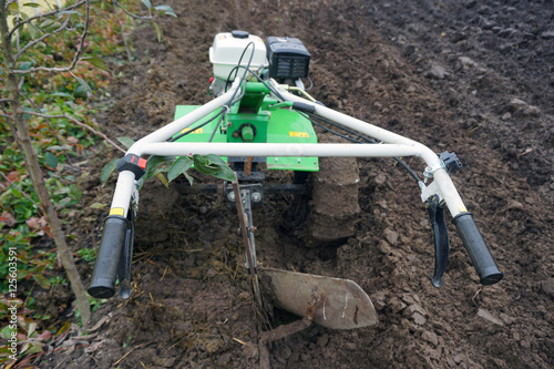 Small hand cultivator tractor in the garden. Autumn harvest work on the field