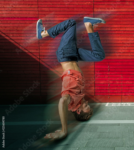Break dancer doing handstand against colorful wall background