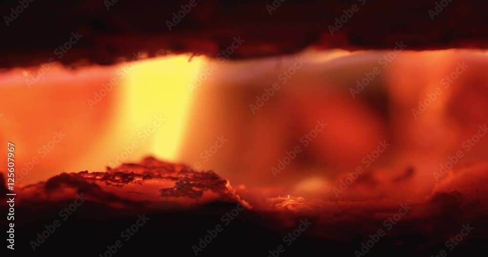 Log burner with macro logs on fire with glowing embers and dancing flame. Filmed in slow motion.