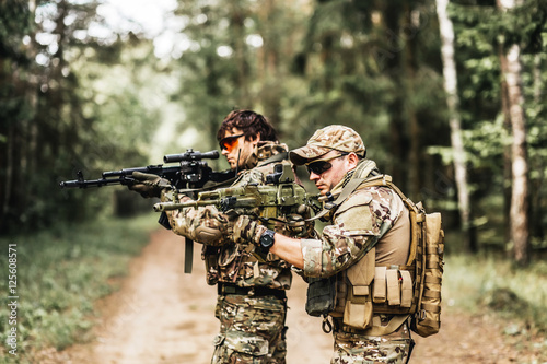 military. Two Armed man in a zone of armed conflict soldier in uniform targeting with assault rifle outdoors. two solders with weapon