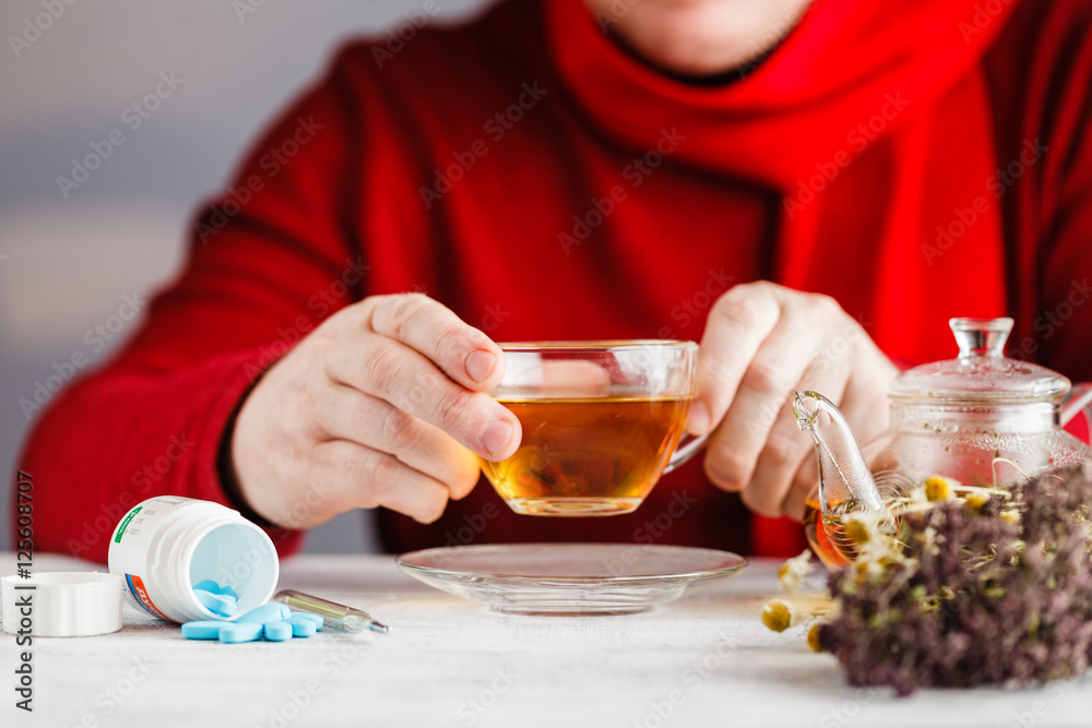Mug with herbal tea and cold, flu medicine on a wooden table. Th