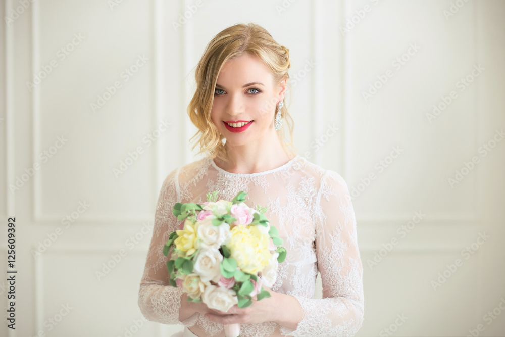 Bride standing with wedding bouquet in white room. Bride standing with wedding bouquet in white room.