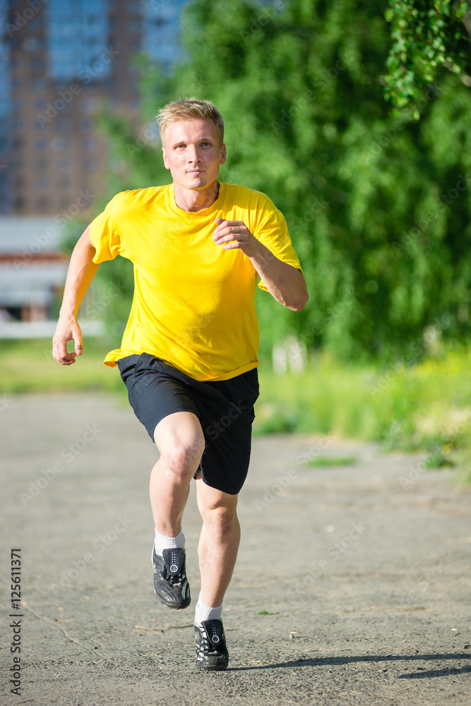 Running man jogging in city street park at beautiful summer day. Sport fitness model caucasian ethnicity training outdoor. Running man jogging in city street park at beautiful summer day. Sport fitness model caucasian ethnicity training outdoor.