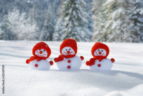 3 Happy Christmas snowmen with snowy fir trees on background