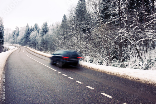 Lonely car in motion blur on the road in winter landscape