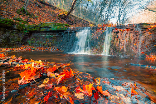 Beautiful view of the pure water waterfall in autumn woodland.