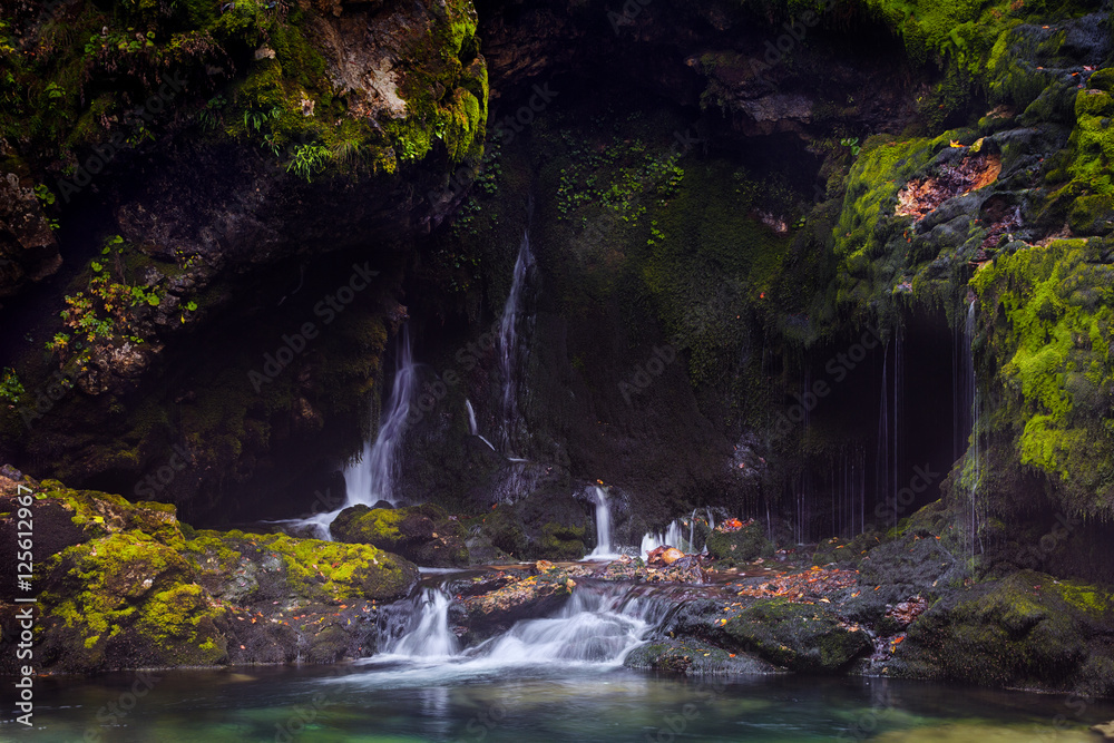 Small waterfall among rocks covered with green moss Small waterfall among rocks covered with green moss