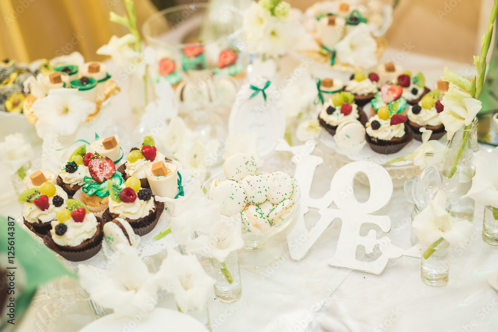 Delicious and tasty dessert table with cupcakes shots at reception closeup Delicious and tasty dessert table with cupcakes shots at reception closeup