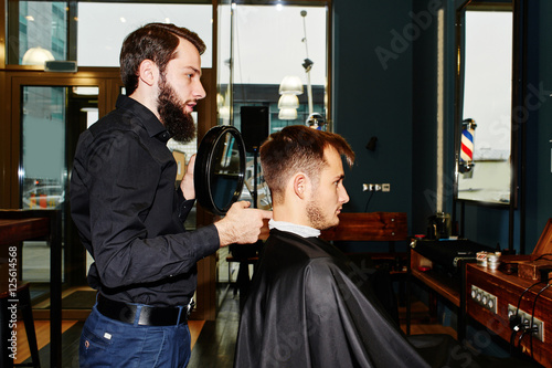 The Barber holds up a mirror and shows real client back in the Barbershop