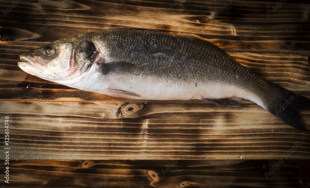 Fresh fish on wooden board. Raw Mediterranean seabass. Fresh fish on wooden board. Raw Mediterranean seabass.