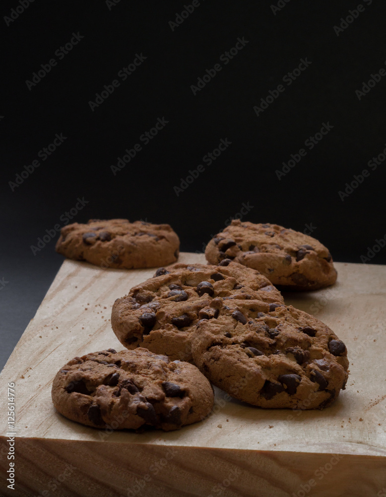 Chocolate cookies on a wooden cutting board. Black background.