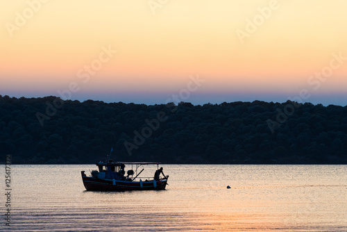 Fisherman working at sunset in Pagasetic gulf, Greece photo