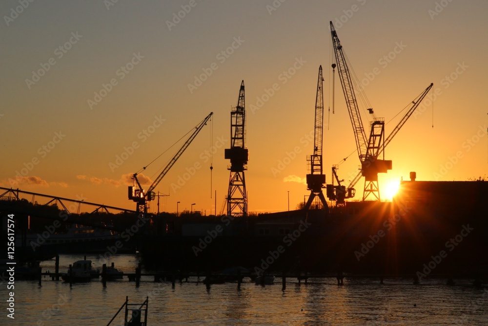 Schiffswerft mit Kränen und untergehender Sonne in Kiel 