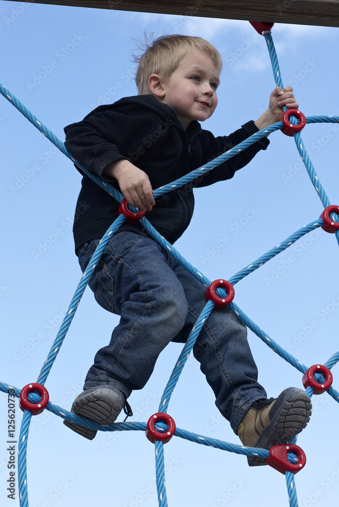 Little child blond boy climbing rope on the playground outdoors
Little child blond boy climbing rope on the playground outdoors