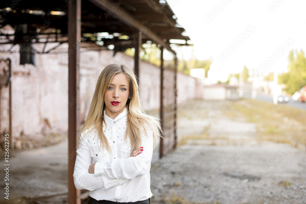 Close-up portrait of a beautiful blonde businesswoman with red lips in a white fashionable office shirt and black leather pants. Youth clothes and office work style. Modern business lady