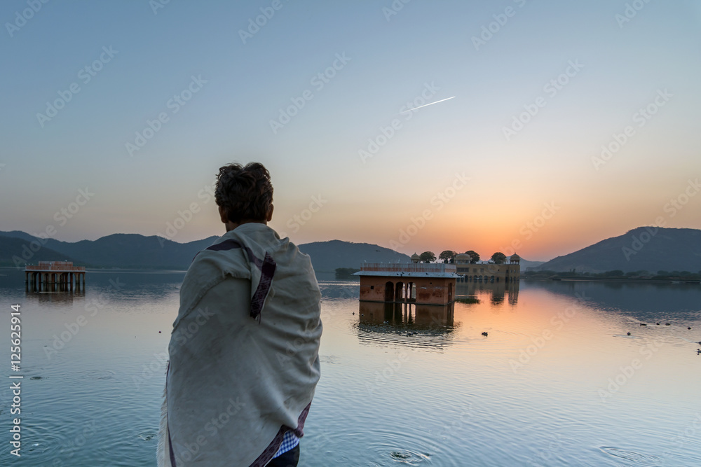 Man looking at  Jal Mahal palace on Man Sagar Lake in Jaipur during the sunrise

