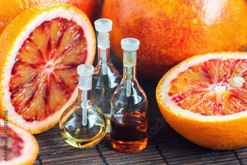 Essential oils in glass bottle with fresh, juicy, ripe, red orange. Beauty treatment. Spa concept. Selective focus.