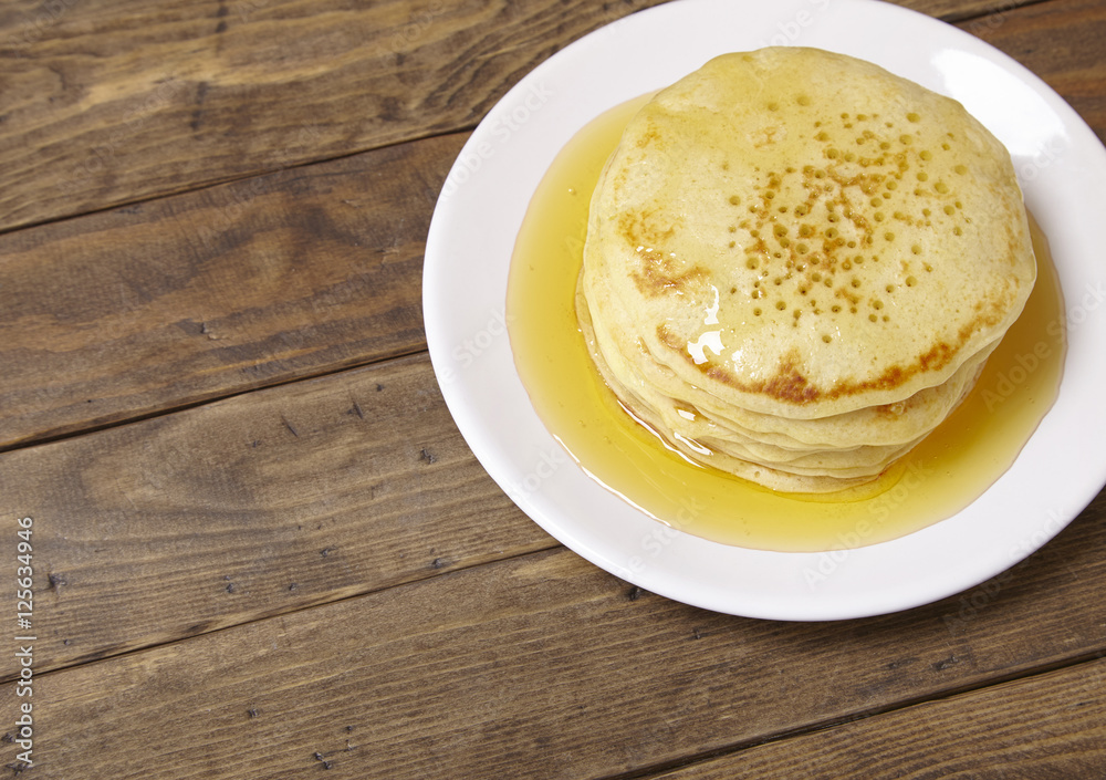 A stack of golden syrup covered pancakes on a wooden breakfast table background forming a page border