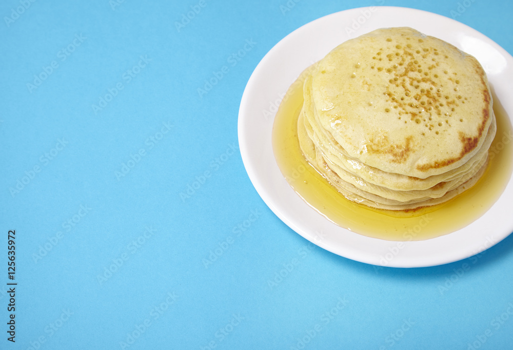 A stack of pancakes with golden syrup on a bright blue background forming a page border
