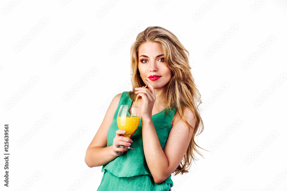 Pretty young beautiful woman drinking orange juice . Girl in green dress hold slass of juice on white background Pretty young beautiful woman drinking orange juice . Girl in green dress hold slass of juice on white background