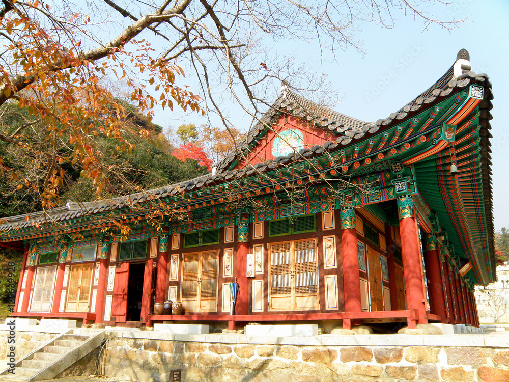 The old buddhism temple with red column under the autumn leaves, South Korea