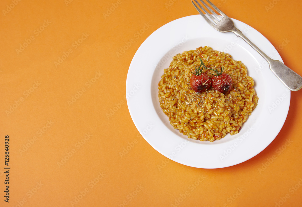 A dinner dish of tomato risotto on a bright orange background forming a page border A dinner dish of tomato risotto on a bright orange background forming a page border