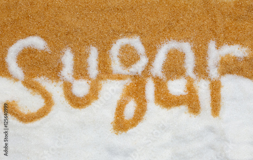 The word sugar written into a pile of white and brown granulated sugar 