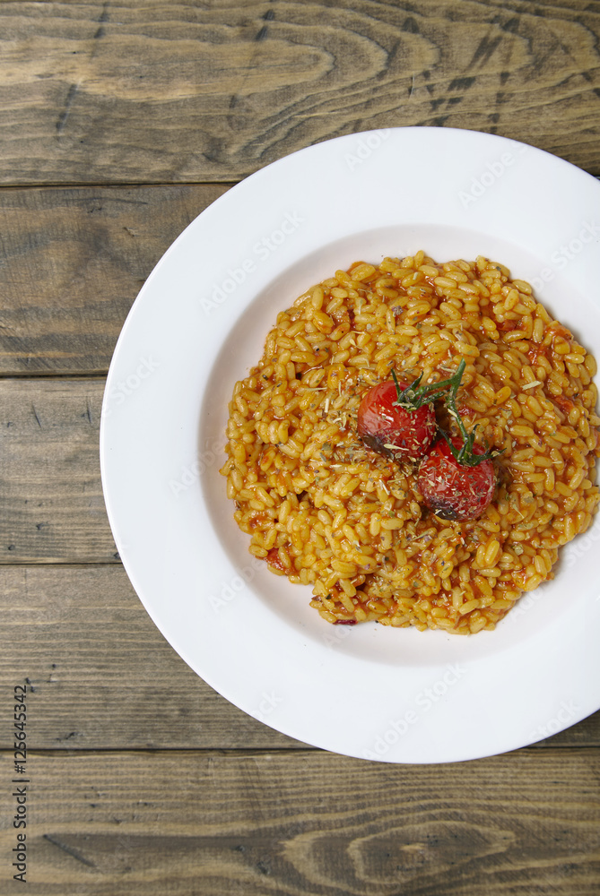 A bowl of tomato risotto on a rustic wooden dinner table background A bowl of tomato risotto on a rustic wooden dinner table background