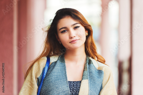 Outdoor fashion portrait of young 20 year old girl wearing grey and beige scarf jacket photo