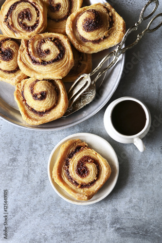 Puff pastry cinnamon rolls on tray with a cup of coffee.Top view photo