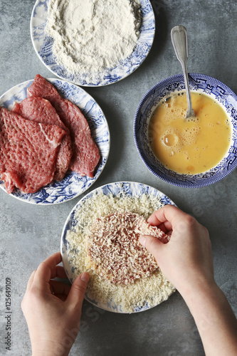 Hands coating beef in breadcrumbs.Preparing schnitzel