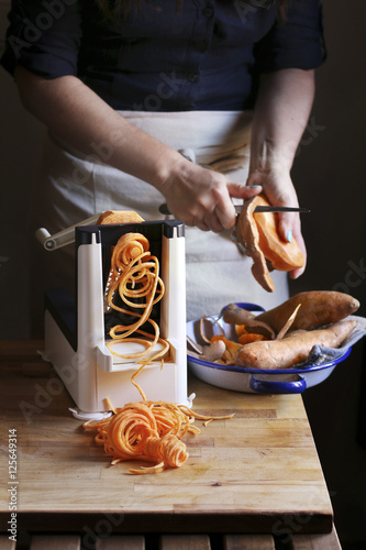 Woman making sweet potato noodle with a spiralizer machine photo