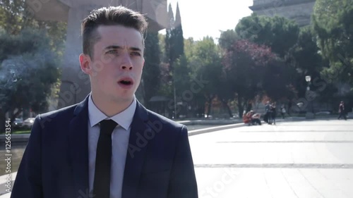 Young business man smoking cigarette in the street