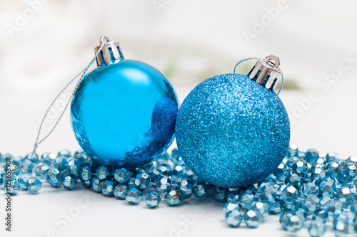 Two blue ornaments ball with tinsel on white table