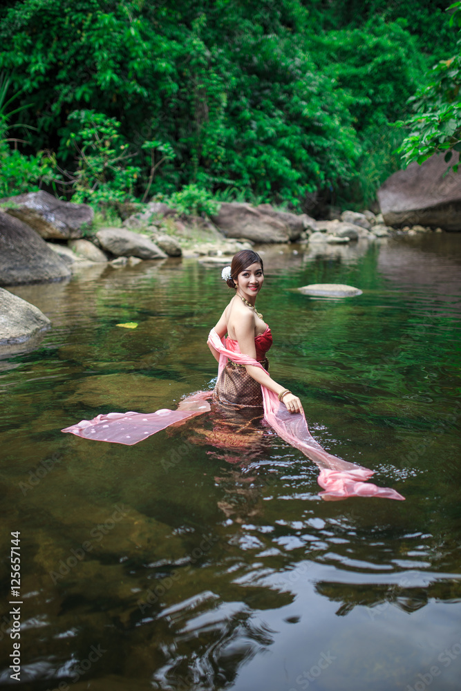 Fototapeta premium Beautiful girl with Thai dressing was playing water in the river.
